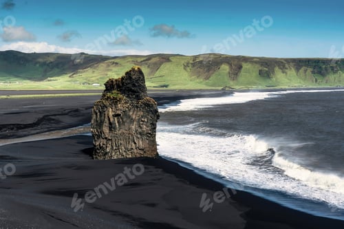 Preview: Kirkjufjara black sand beach with eagle rock mountain and big wave crashing in summer at Iceland