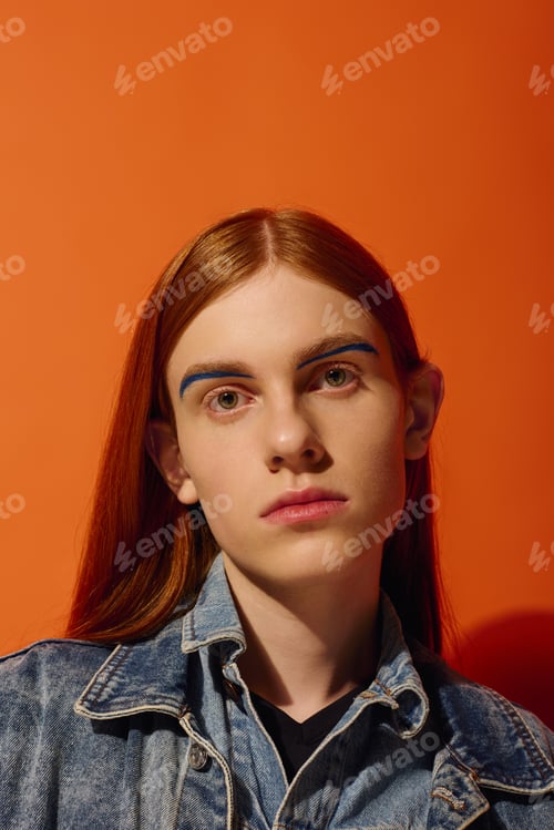 Preview: Emotion radiates from a young man with long red hair against a vibrant orange backdrop