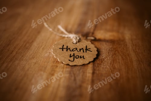 Preview: Thank you word written in a card on wooden background. Love and gratitude concept.