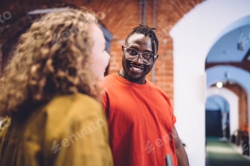 Preview: Cheerful young black male student enjoying conversation with friend in campus