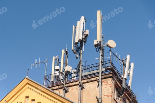 Preview: Cluster of mobile network broadcast cell repeaters on roof of building in city.