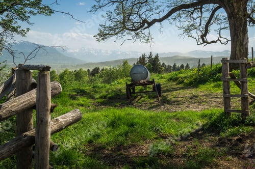 Preview: Metal cistern on wheels in a meadow with mountins in the background