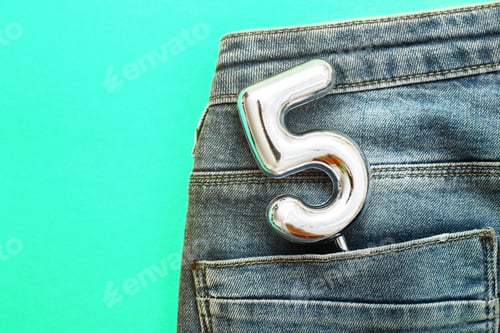 Preview: number 5 sticking out of the back pocket of blue jeans on green background