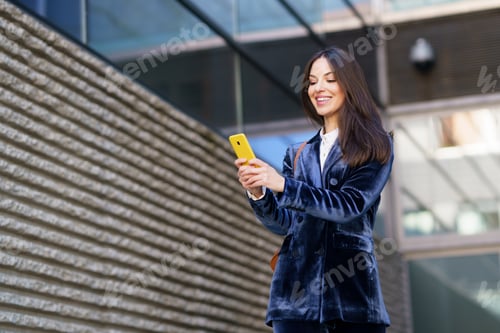 Preview: Business woman wearing blue suit using smartphone in an office building.