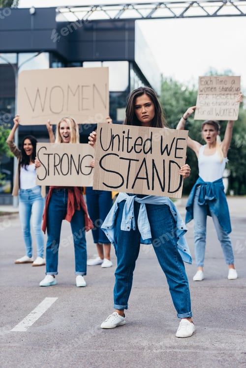 Preview: full length view of feminist holding placard with inscription united we stand near women on street