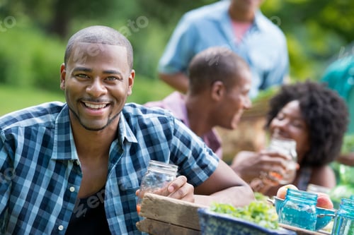 Preview: A group of adults and young people at a meal in the garden of a farmhouse.