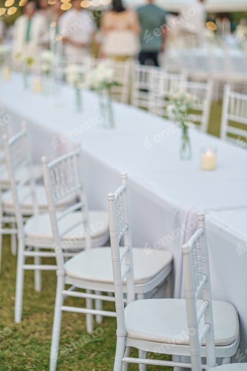 Preview: Elegant wedding long table with candle, white rose flower and white chairs in the garden