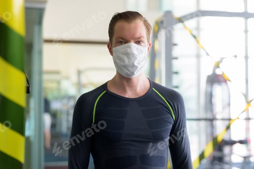 Preview: Young man with mask for protection from corona virus outbreak at gym during corona virus covid-19