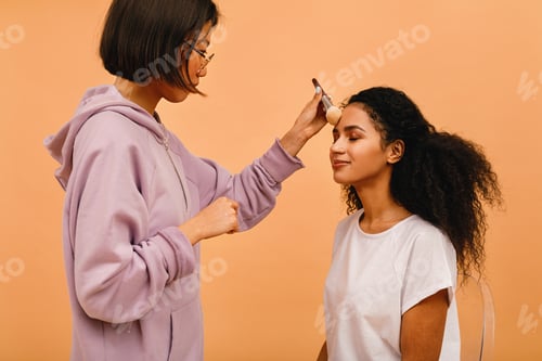Preview: Professional make up artist applying tonal powder on model in studio