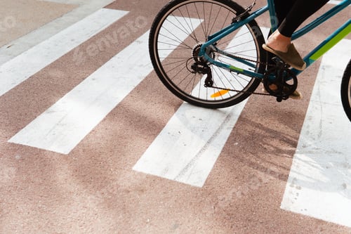 Preview: Close-up view of a woman's feet as she rides a bicycle across a pedestrian crossing