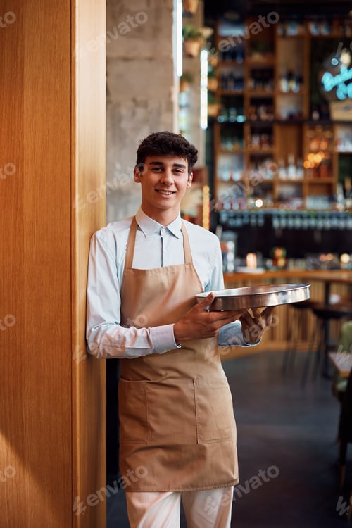 Preview: Portrait of happy waiter in a cafe looking at camera.
