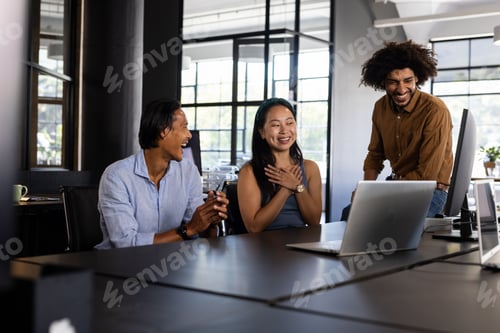 Preview: Diverse business team laughing together during meeting in modern office