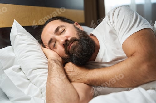 Preview: Bearded man sleeps in a bright hotel room