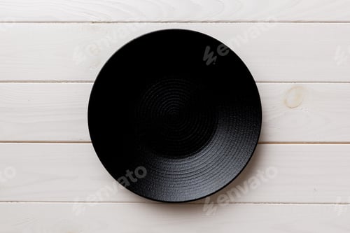 Preview: Top view of black plate on wooden background. Empty space for your design