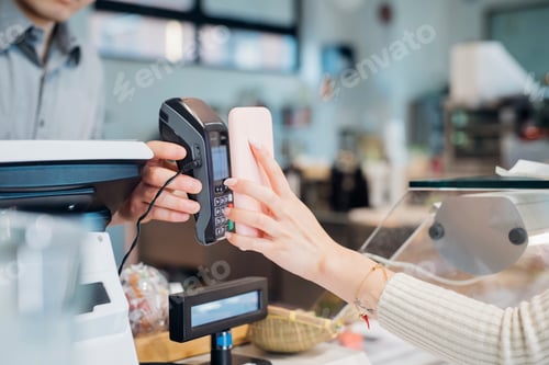 Preview: Young businesswoman making smartphone payment at cafe counter, cropped
