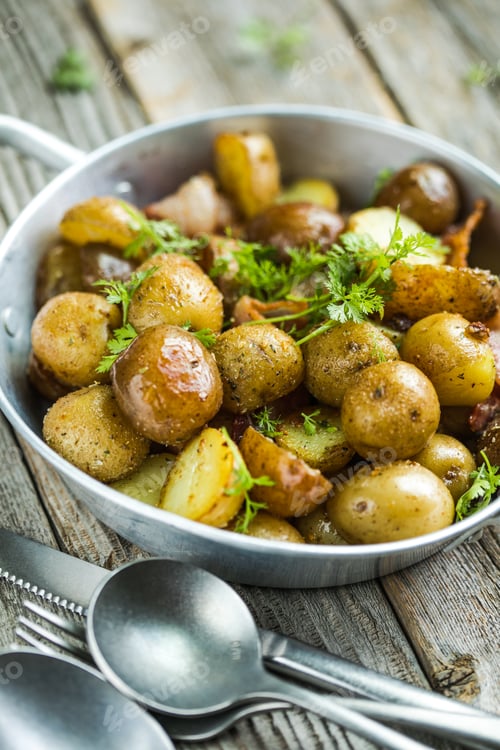 Preview: Baby young potatoes, bacon, parsley on a frying pan on a wooden background, close-up