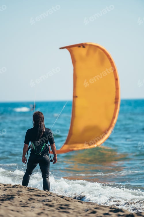 Preview: Woman wearing kite harness and a wetsuit on a beach