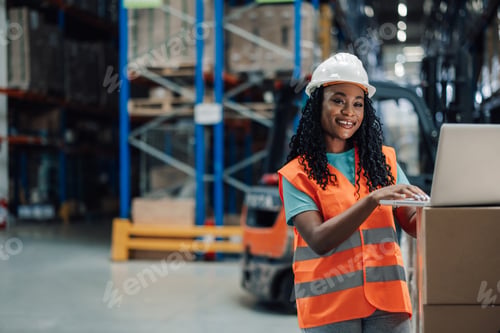 Preview: Young female worker using laptop in warehouse
