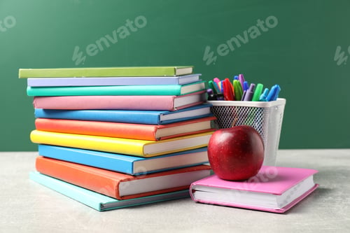 Preview: Different school stationery and red apple on grey table against blackboard