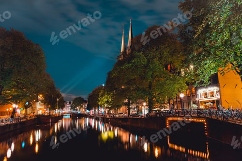Preview: Night shot of Amsterdam canal with illuminated steeples of the church De Krijtberg in downtown