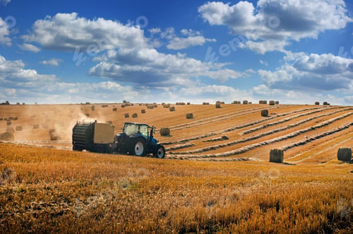 Preview: tractor forms bales on the hills of straw field, beautiful sky