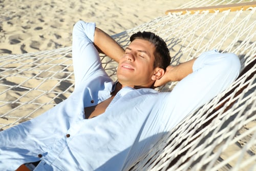 Preview: Handsome man relaxing in hammock on beach