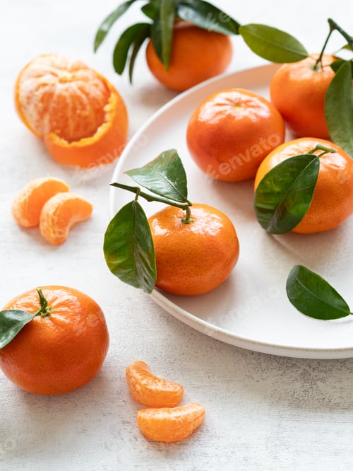 Preview: Fresh tangerines with leaves on white plate and table