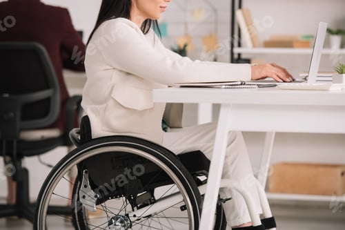 Preview: cropped view of disabled businesswoman sitting in wheelchair at workplace