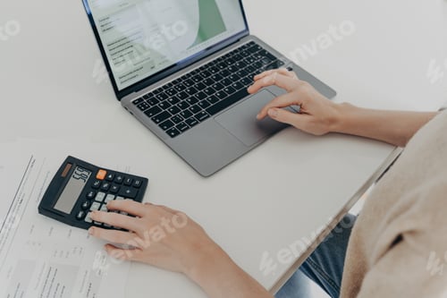 Preview: Close-up of hands using calculator and laptop on white desk, concept of finance, budgeting
