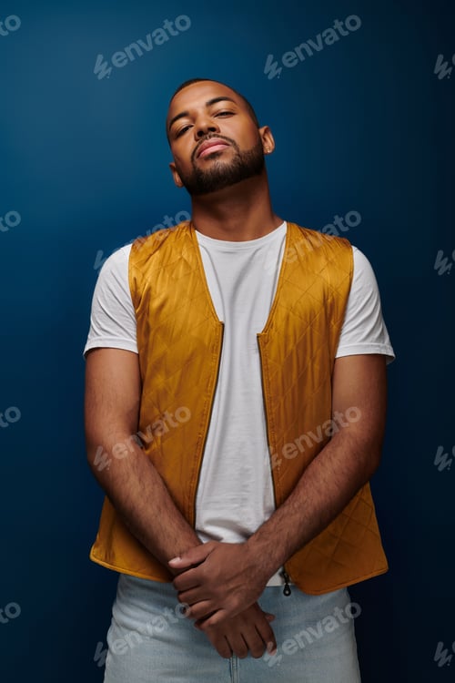 Preview: handsome african american man in vest posing standing still on dark blue background, fashion concept