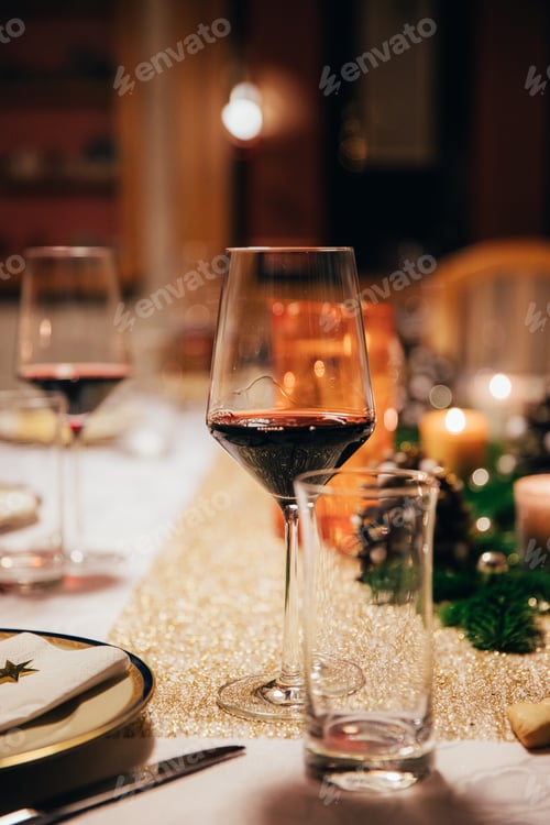 Preview: Close up of glass with red wine on festively decorated christmas dinner table