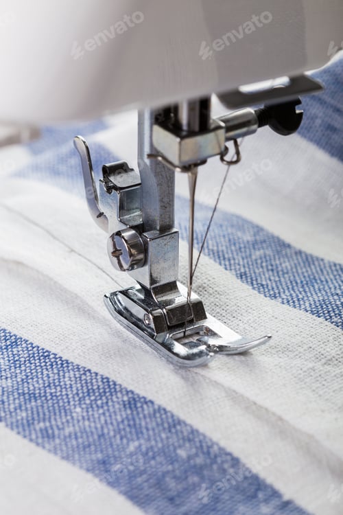 Preview: Close-up view of sewing machine needle working on striped fabric during daylight