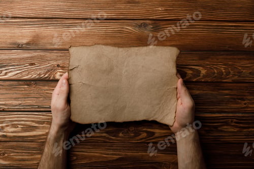 Preview: top view of man holding aged paper sheet in hands
