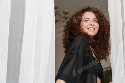 Preview: Cheerful woman in lingerie swimwear posing indoors in home hotel near curtain.