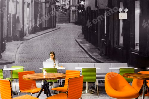 Preview: Woman using laptop while siting against wall at coffee shop