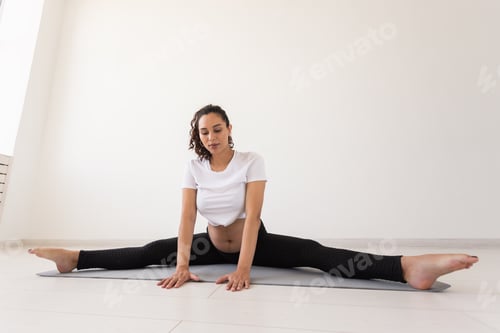 Preview: Purposeful pregnant woman exercises during yoga class and relaxes while sitting on a mat on the