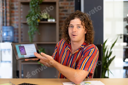 Preview: Portrait of happy caucasian casual businessman making video call, talking and showing tablet