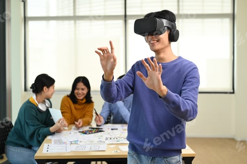 Preview: Excited creative business man wearing VR headset and touching on the air, standing in meeting room.