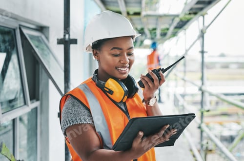 Preview: Shot of a young woman using a digital tablet and walkie talkie while working at a construction site