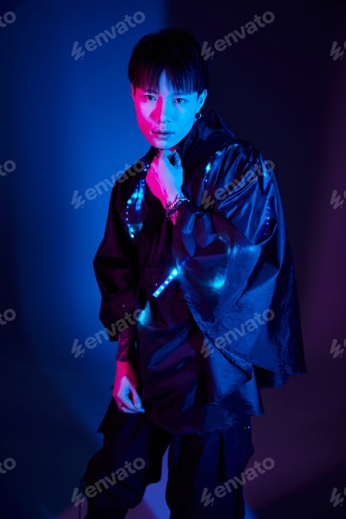 Preview: Stylish young man showcasing modern fashion in vibrant lighting during a creative photoshoot