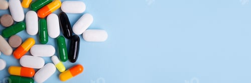 Preview: Top view of different pills on blue background,large banner with negative space.