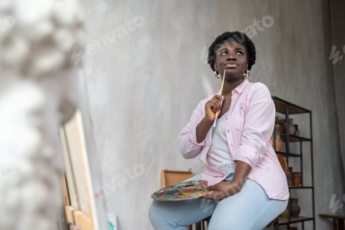 Preview: Inspiration. Contented african artist in pink clothes looking inspired