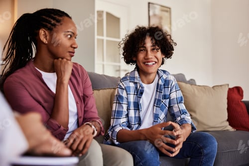 Preview: An African mother looking at her happy son and sitting next to him on a couch.