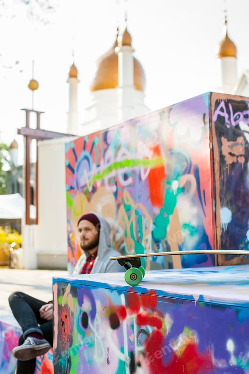 Preview: Young man sitting at skateboard park