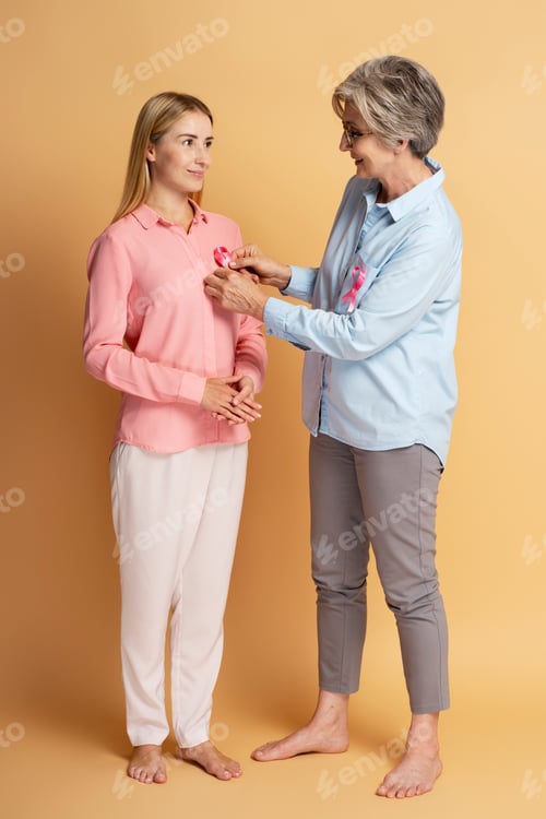 Preview: Women attach pink ribbon isolated on background. Health care. Breast cancer awareness month