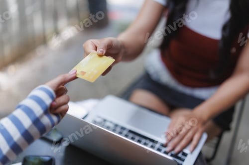 Preview: Woman paying with credit card on laptop in outdoor cafe