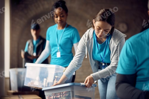 Preview: Young volunteer packing box of donated clothes at community center.