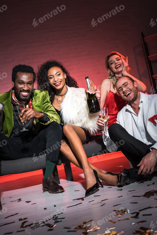 Preview: low angle view of african american woman holding bottle while sitting near multicultural friends