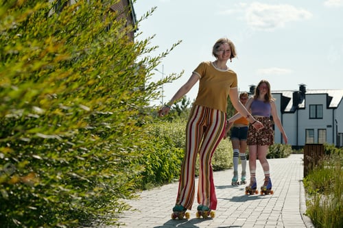 Preview: Young woman in casualwear moving along road on roller skates