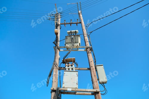 Preview: Electric transformer on wooden poles, blue sky background
